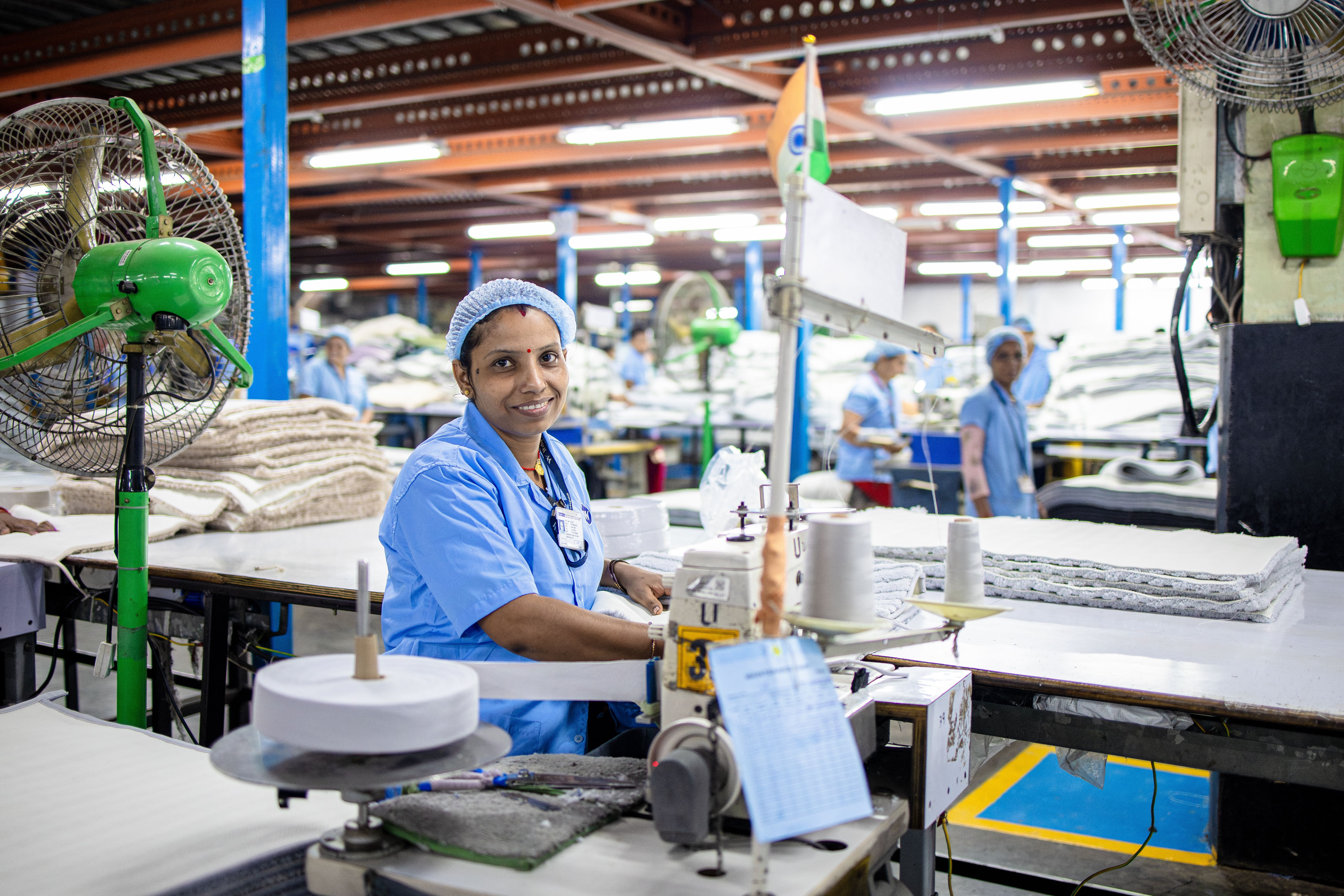 Operator at a stitching machine on a busy textile floor